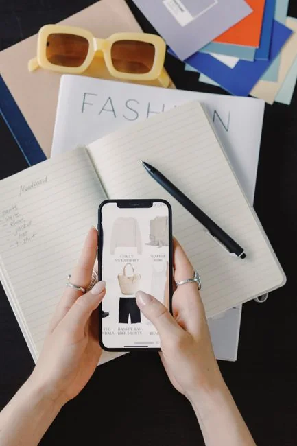 Gros plan d’un carnet avec des esquisses de wireframe et un smartphone posé sur un bureau en bois.